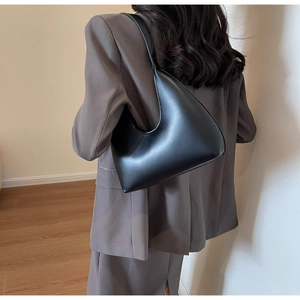 Sac à bandoulière demi-lune noir minimaliste en cuir mat porté par un mannequin stylé