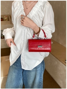 Detail of red crocodile texture handbag with metallic silver twist lock and handle