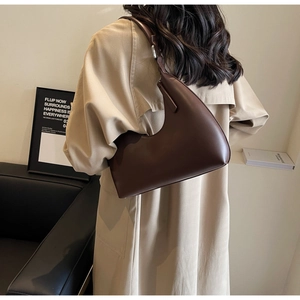 Détail du sac à bandoulière demi-lune marron foncé porté avec un style rétro minimaliste