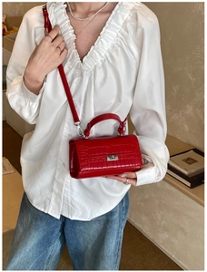 Red crocodile texture bag shown on model with vintage shirt and casual blue jeans