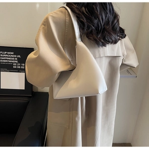 Vue latérale d'un sac à bandoulière minimaliste crème en forme de croissant sur un modèle
