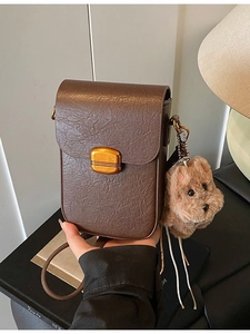 Vintage brown textured crossbody phone bag with gold clasp and plush dog charm accessory