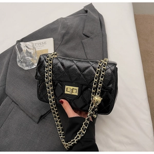 Detail of black quilted patent leather bag with gold chain strap and gold ball charm