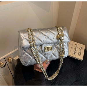 Detailed macro view of silver quilted leather with golden chain and adjustable metal ball