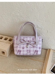 Detail of purple plaid handbag with cute 3D bow and metal heart charm on a textured wall