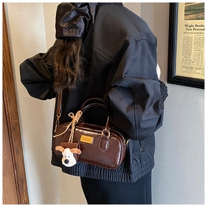 Detail of vintage dark brown faux leather bowling bag with cute puppy plush keychain