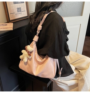 Close-up of pink hobo bag with unique knotted strap and cute plush bear charm detail