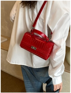 Detail of red crocodile texture handbag with silver metallic twist lock on a white shirt