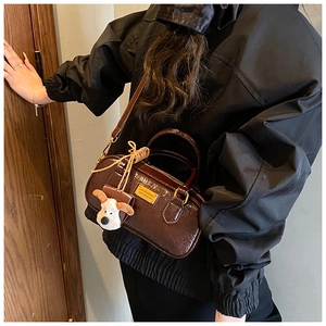 Detail of vintage brown bowling bag with glossy finish and cute dog plush pendant charm