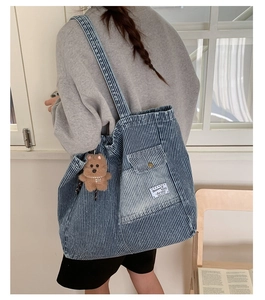 Detail of blue denim tote bag with white stripes and cute brown teddy bear keychain