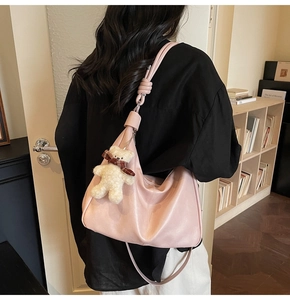 Detail of pink half-moon slouchy bag featuring a leather texture and knot design