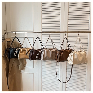 Close-up of pleated leather shoulder bags in six various colors hanging on a rack