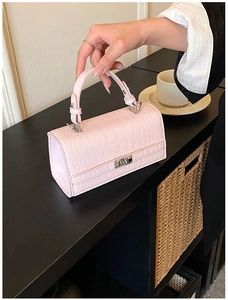Close-up of pink crocodile texture leather handbag with silver metal twist lock closure