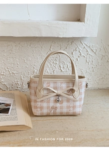Detail of quilted checkered handbag with bow accent and heart charm decoration