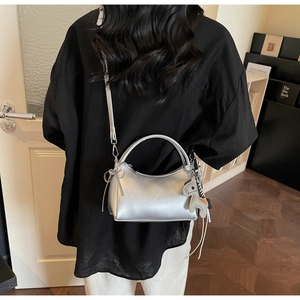 Detalle del bolso de media luna plateado con colgante de caballo y lazo suave