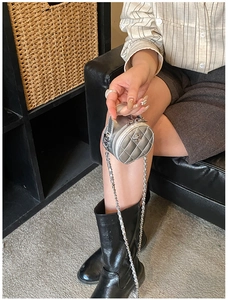 Détail du mini sac rond argenté matelassé avec chaîne en métal et motif de camélia