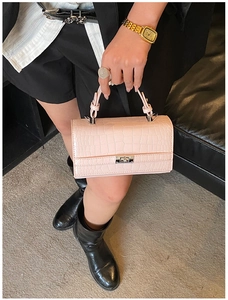Detail shot of pink crocodile pattern leather handbag with silver metallic turn-lock closure