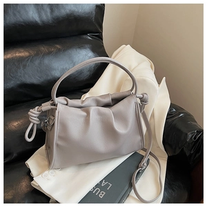 Detailed close-up of light purple pleated leather bag on a white suit with soft shadows