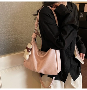 Pink hobo shoulder bag with white teddy bear charm shown in a casual lifestyle setting