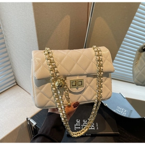 Detail of gold metal twist lock and quilted faux leather texture on ivory chain bag