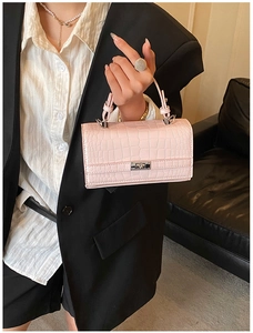 Model holding a small pink faux crocodile skin handbag with silver clasp closure