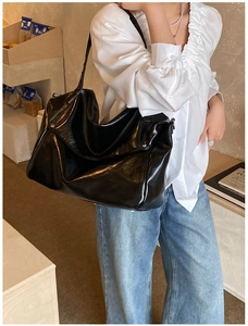 Detail of black large capacity tote bag featuring glossy texture and rivet craftsmanship