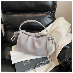 Minimalist light grey pleated cloud bag with knot details on a stylish suit background