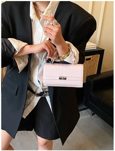 Detail of light pink crocodile pattern handbag with silver square twist lock closure