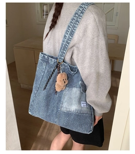 Detail of striped denim canvas tote bag with outer pocket and plush bear pendant