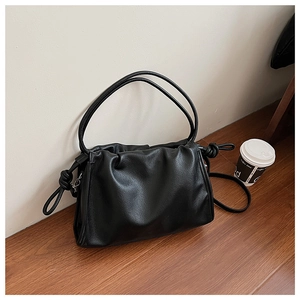 Close-up of black pleated faux leather underarm bag with knot drawstrings and soft texture