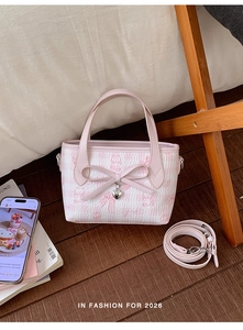 Detailed shot of pink plaid tote bag featuring bow accents and heart-shaped metal charms