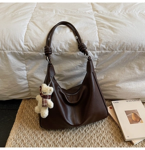 Detail shot of vintage dark brown tote bag with knot strap and plush bear charm decoration