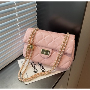 Detailed view of pink quilted handbag featuring gold chain strap and metallic twist lock