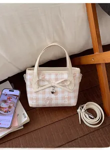 Detailed view of cream and pink checkered bag with heart pendant and ribbon bow
