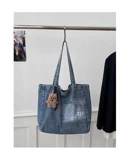 Detail of blue corduroy tote bag with white stripes and cute brown teddy bear keychain