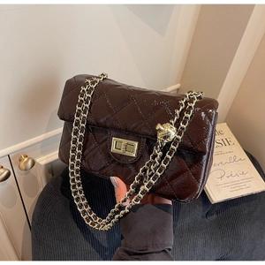 Close-up of dark brown patent leather quilted bag with gold chain and square metal clasp