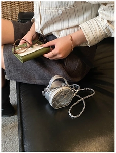 Gros plan d'un mini sac rond argenté montrant la texture matelassée et le logo camélia