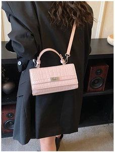 Detail of pink crocodile pattern handbag with silver rotary lock shown on model
