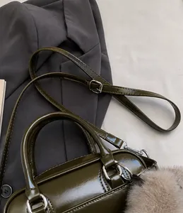 Detail of dark green patent leather handbag featuring an adjustable shoulder strap