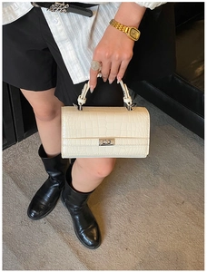 Detail view of retro crocodile pattern handbag in cream white with silver twist lock buckle