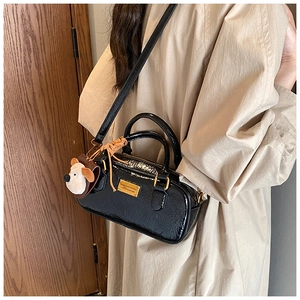 Detail view of black glossy bowling bag with cute puppy pendant and gold metal tag