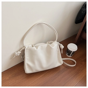 Detail of off-white lychee grain leather bag with pleated closure and knot shoulder strap