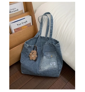 Detailed texture of blue striped denim tote bag with cute bear charm on a wood floor