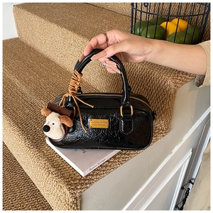 Detail of a black vintage bowling bag with a plush puppy charm on stairs