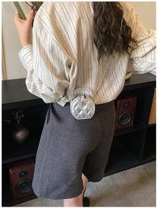 Détail du mini sac rond matelassé argenté avec camélia et bandoulière chaîne