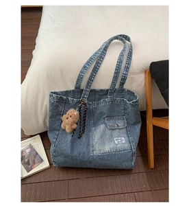 Close-up of striped denim tote bag with front pocket and plush teddy bear charm