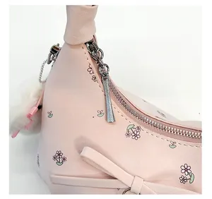 Détail de la fermeture éclair métallique sur sac à main rose fleuri avec nœud élégant