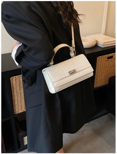 Detail of white crocodile pattern PU handbag featuring a polished silver twist lock closure