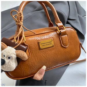 Macro detail of caramel PU bowling bag featuring glossy crinkled texture and golden logo plate