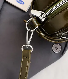 Detail of silver metal hooks and premium stitching on dark green leather shoulder bag